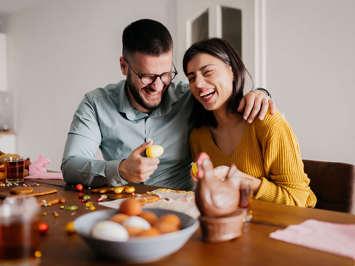 Happy couple enjoying colorful Easter eggs together at home, smiling and sharing a joyful moment