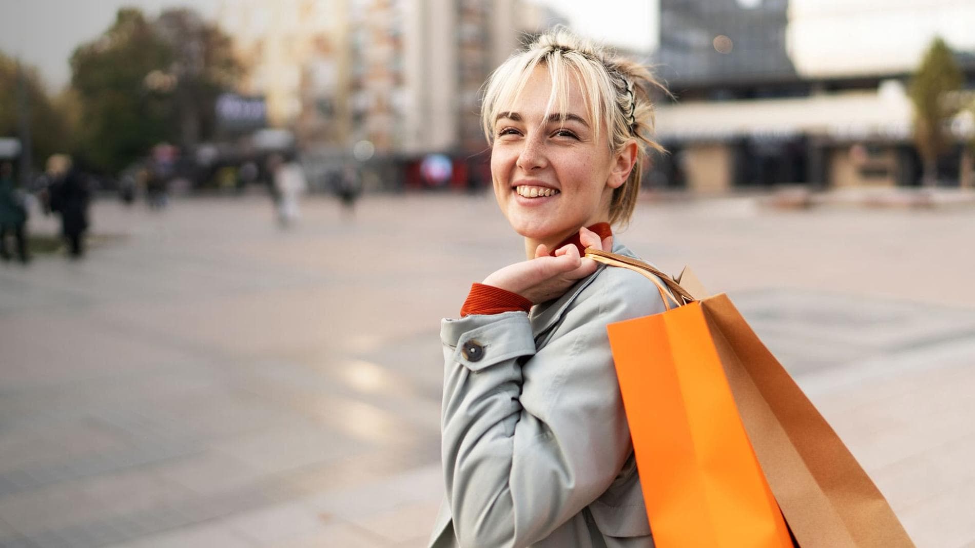 A smiling woman holds several shopping bags, showcasing her joy after a successful shopping trip